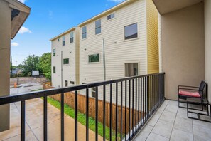 Un edificio residencial con balcón, cerca de madera y un pequeño patio.