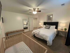 Cozy retreat with a large bed, crib, and comfortable seating area.