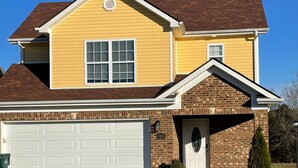 A two-story house with a garage, a brick section on the front, and a well-maintained lawn. - Cheerful Three-Bedroom Residential Home (Richmond)