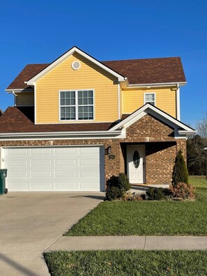 A charming two-story home with a garage and a well-manicured lawn.