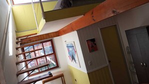 Une chambre de dortoir avec des lits superposés, une fenêtre, une porte et un mur orné d’une affiche.