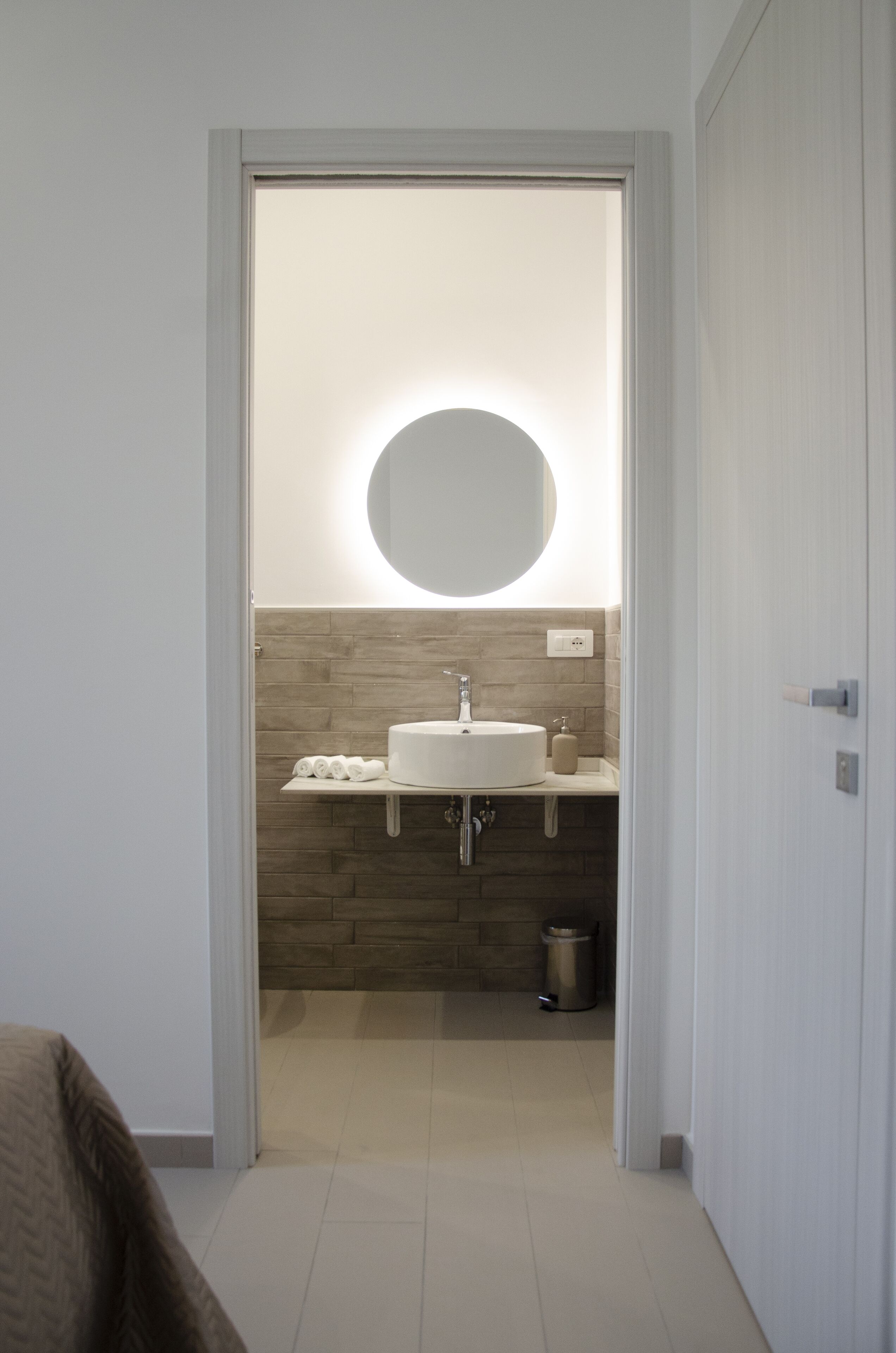 A bathroom with a white sink, a round mirror, and a towel rack.