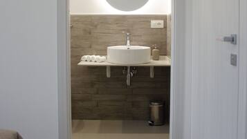 A bathroom with a white sink, a round mirror, and a towel rack.