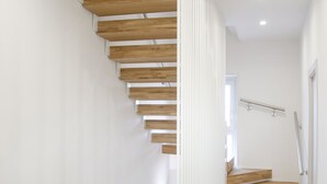 Una escalera moderna con escalones de madera y paredes blancas, que sube a un piso superior.