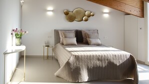 Un dormitorio con cama, mesitas de noche, un adorno en la pared y una ventana.