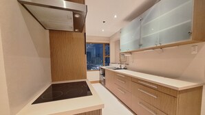 Cozinha moderna com fogão embutido, armários de madeira e vista da cidade à noite.