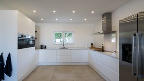 A modern kitchen with white cabinetry, a stainless steel refrigerator, and a window with a view of greenery.
