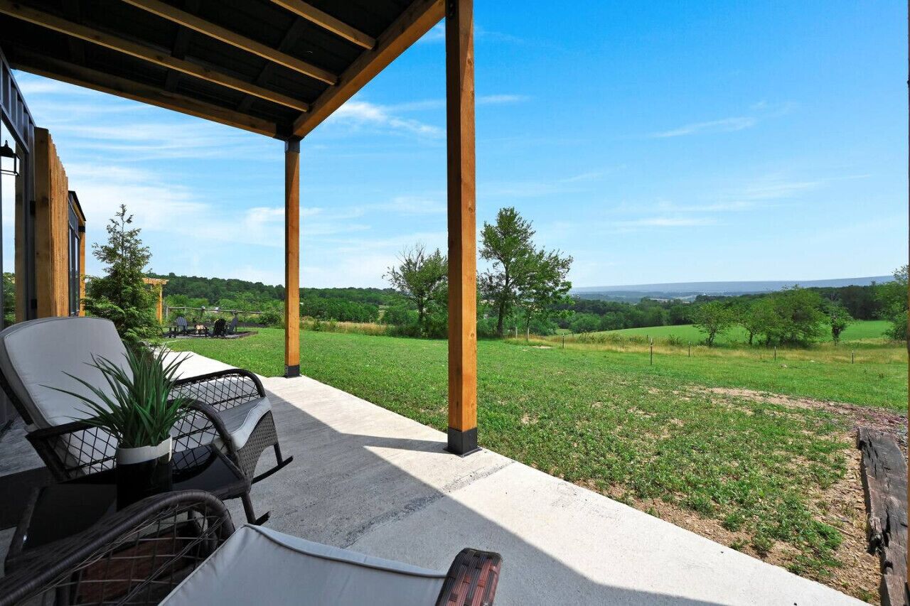 Eine überdachte Terrasse mit Gartenmöbeln und Blick auf eine grüne Landschaft.