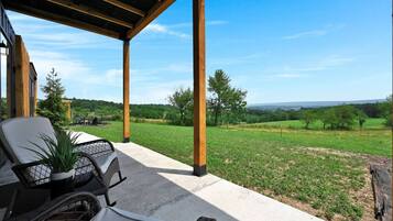 Eine überdachte Terrasse mit Gartenmöbeln und Blick auf eine grüne Landschaft.