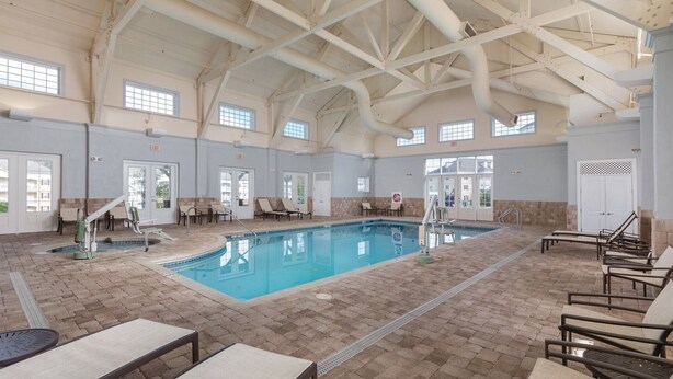 A large indoor swimming pool with multiple exits, lounge chairs, and a tiled floor. - 1BD/Williamsburg at Governor's Green - Lots to do! (Williamsburg)