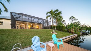 A modern house with a covered patio, a small pool, and outdoor seating. - Villa Sunset with heated Pool and Privacy on the canal (Cape Coral)