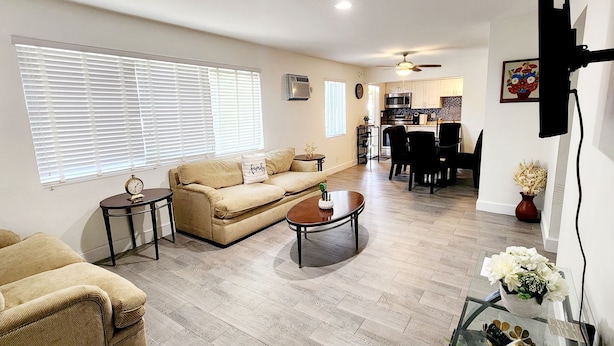 Una sala de estar con un sofá color beige, una mesita de centro y un comedor con mesa y sillas.