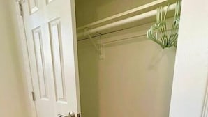Puerta cerrada que da a un armario con barra para colgar y una planta.