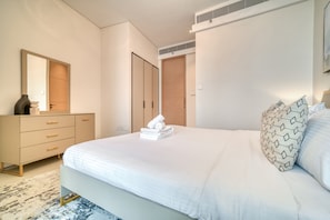 A modern bedroom with a large bed, a dresser, and a mirror.