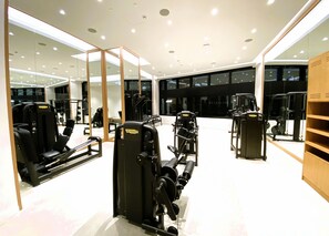 Ein modernes Fitnessstudio mit verschiedenen Trainingsgeräten, großen Spiegeln und einer großzügigen Gestaltung.