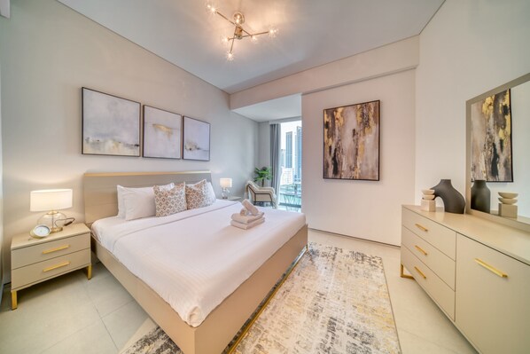 A modern bedroom with a large bed, bedside tables, a dresser, and artwork on the walls.