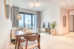 Ein modernes Wohnzimmer mit Essbereich, großen Fenstern, einem Flachbildfernseher und einer Topfpflanze.