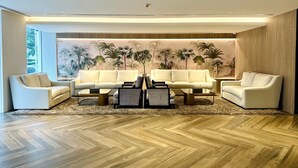 A modern living room with two sofas, a coffee table, and a large tropical mural on the wall.