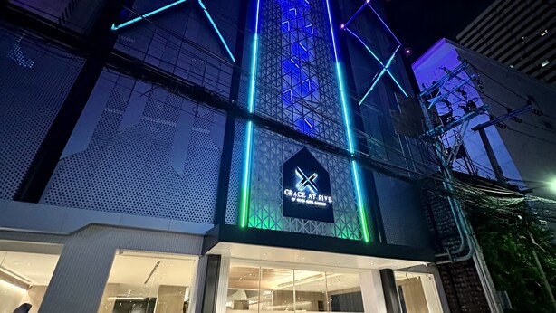 A building with a prominent X-shaped sign and illuminated geometric patterns on its facade.