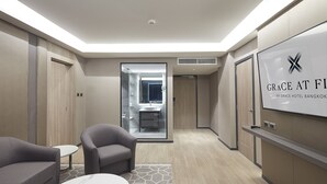 A modern hotel lobby with a reception desk, seating area, and a large mirror.