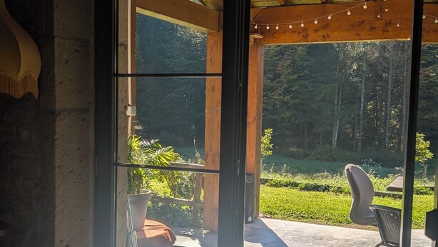 Un intérieur en bois avec une porte-fenêtre coulissante donnant sur un patio extérieur.