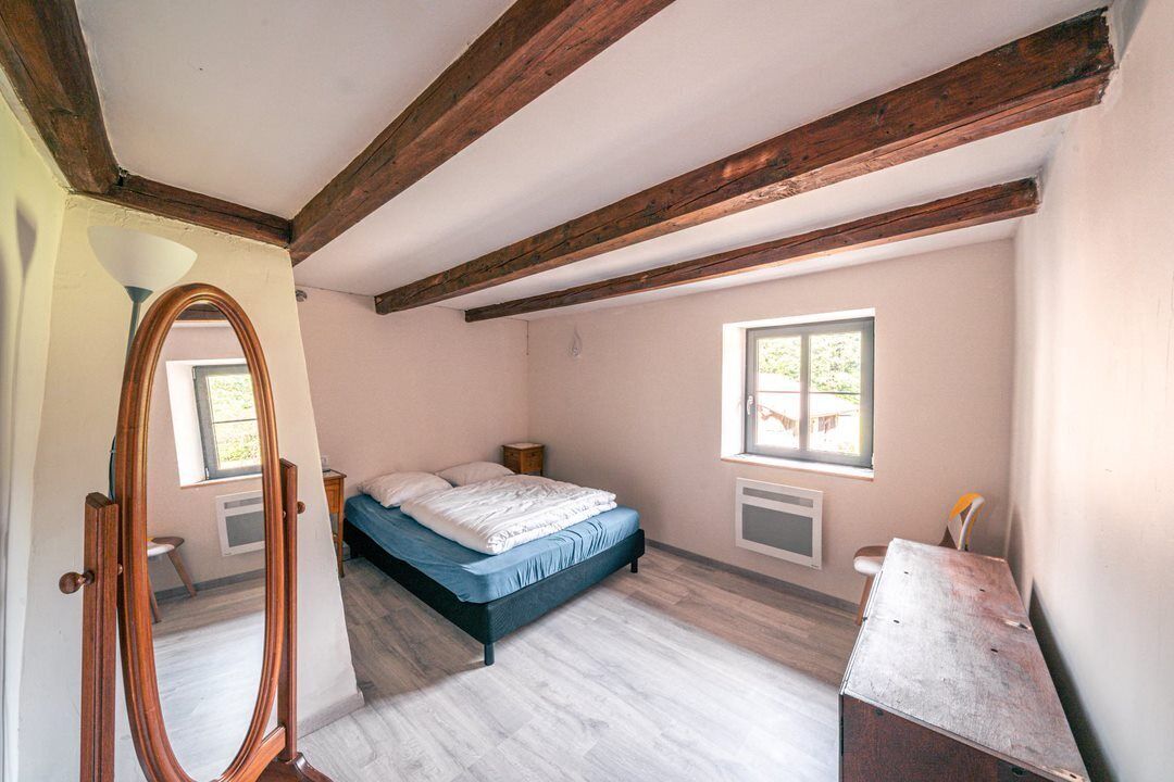Un dormitorio con una cama, un aparador de madera, un espejo y una ventana.
