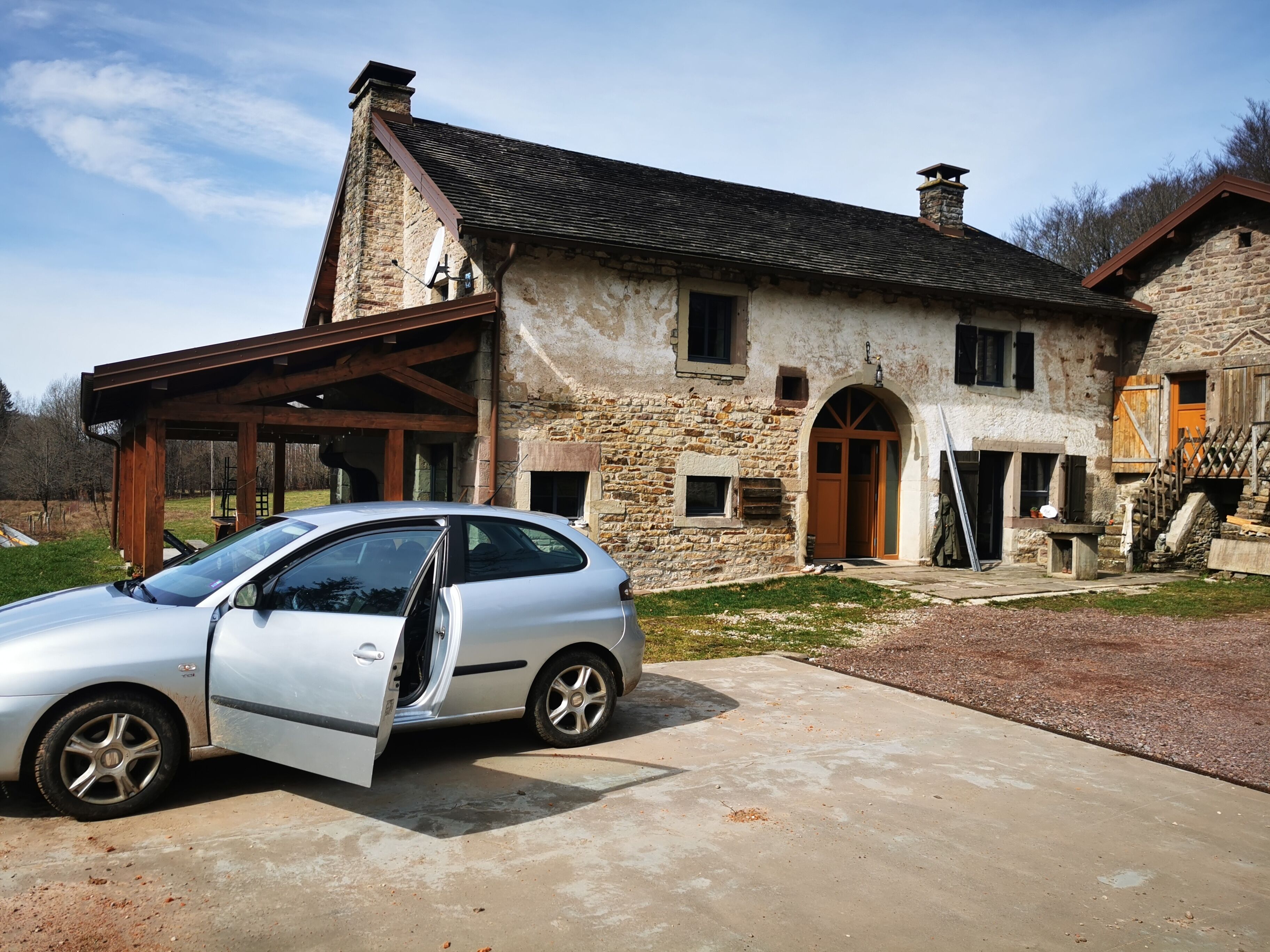 A stone house with a car parked in front.