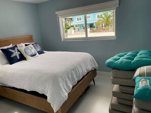 A bedroom with a bed, pillows, a window, and a view of a building outside.