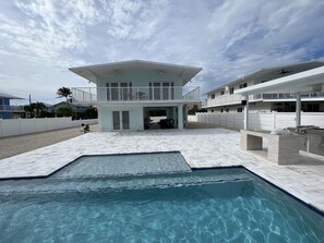 Et moderne hus med swimmingpool, overdækket terrasse og balkon.