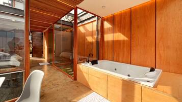 Ein modernes Badezimmer mit einer großen Badewanne, Holzvertäfelung und einer Duschkabine aus Glas.