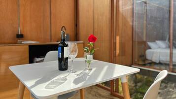 Un tavolo con una bottiglia di vino, un bicchiere da vino e un vaso con una singola rosa rossa.