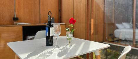 A table with a bottle of wine, a wine glass, and a vase with a single red rose.