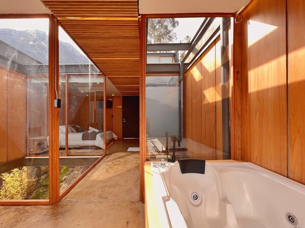 Un baño moderno con una bañera grande, paredes de madera y una zona de ducha con cerramiento de vidrio.