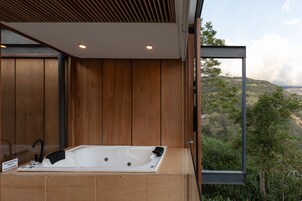 Un baño moderno con detalles de madera, una bañera grande y vistas a un paisaje montañoso.