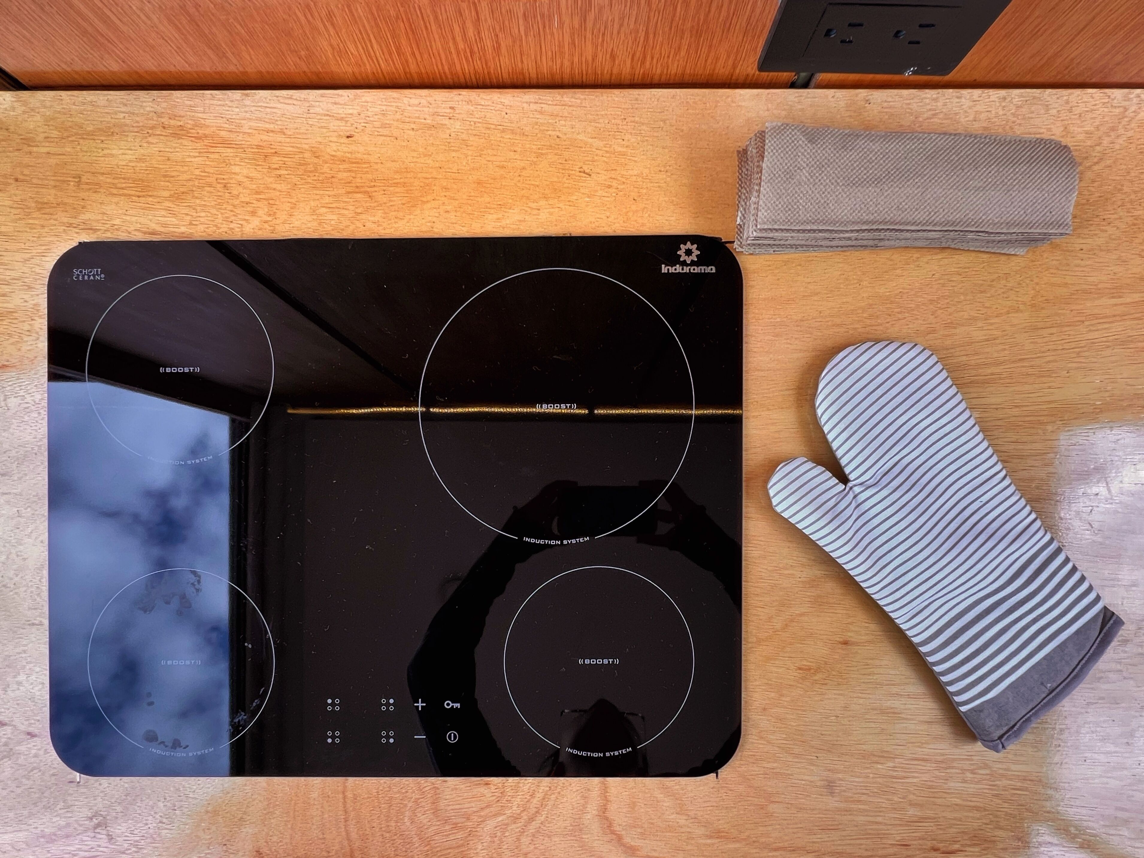 A kitchen with a black induction cooktop, a microwave, and a stainless steel oven.