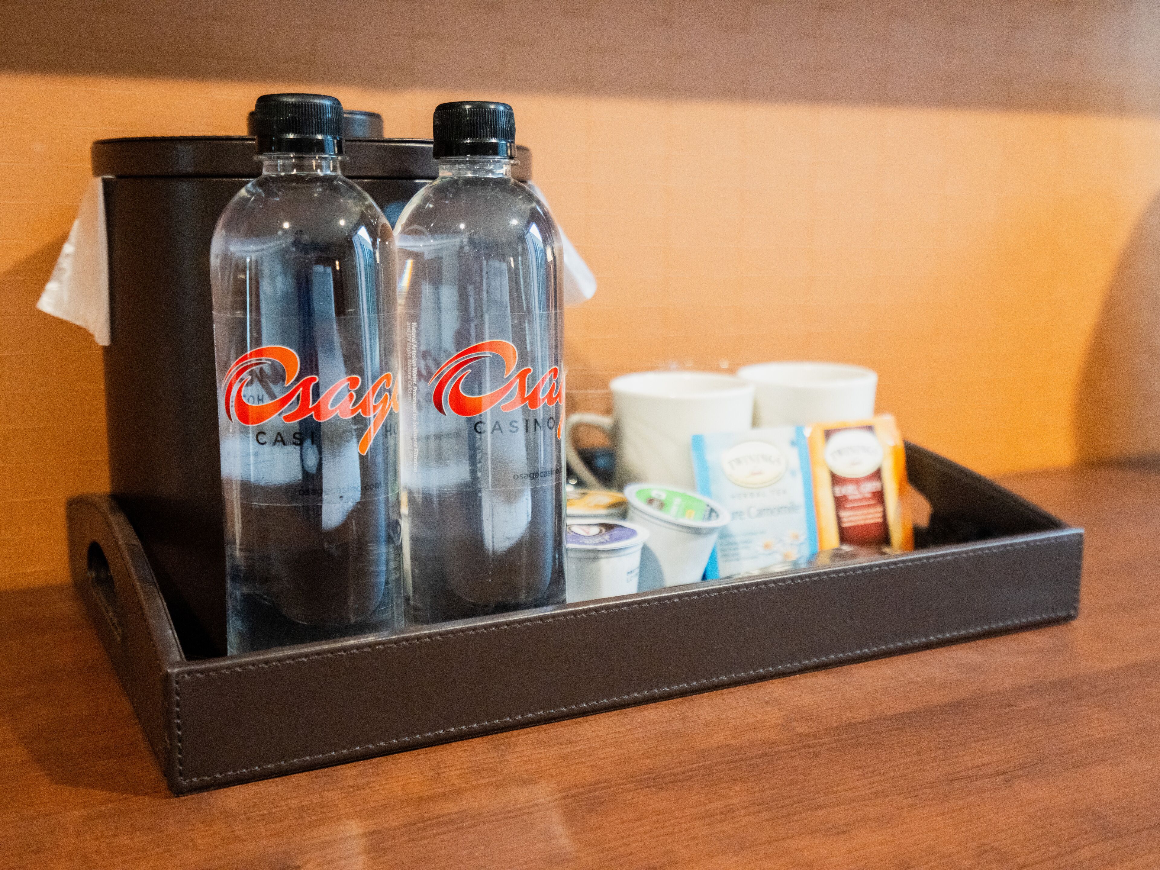 Una bandeja con dos botellas etiquetadas como 'Osage Casino' y diversos alimentos, incluyendo yogur y bocadillos envasados.