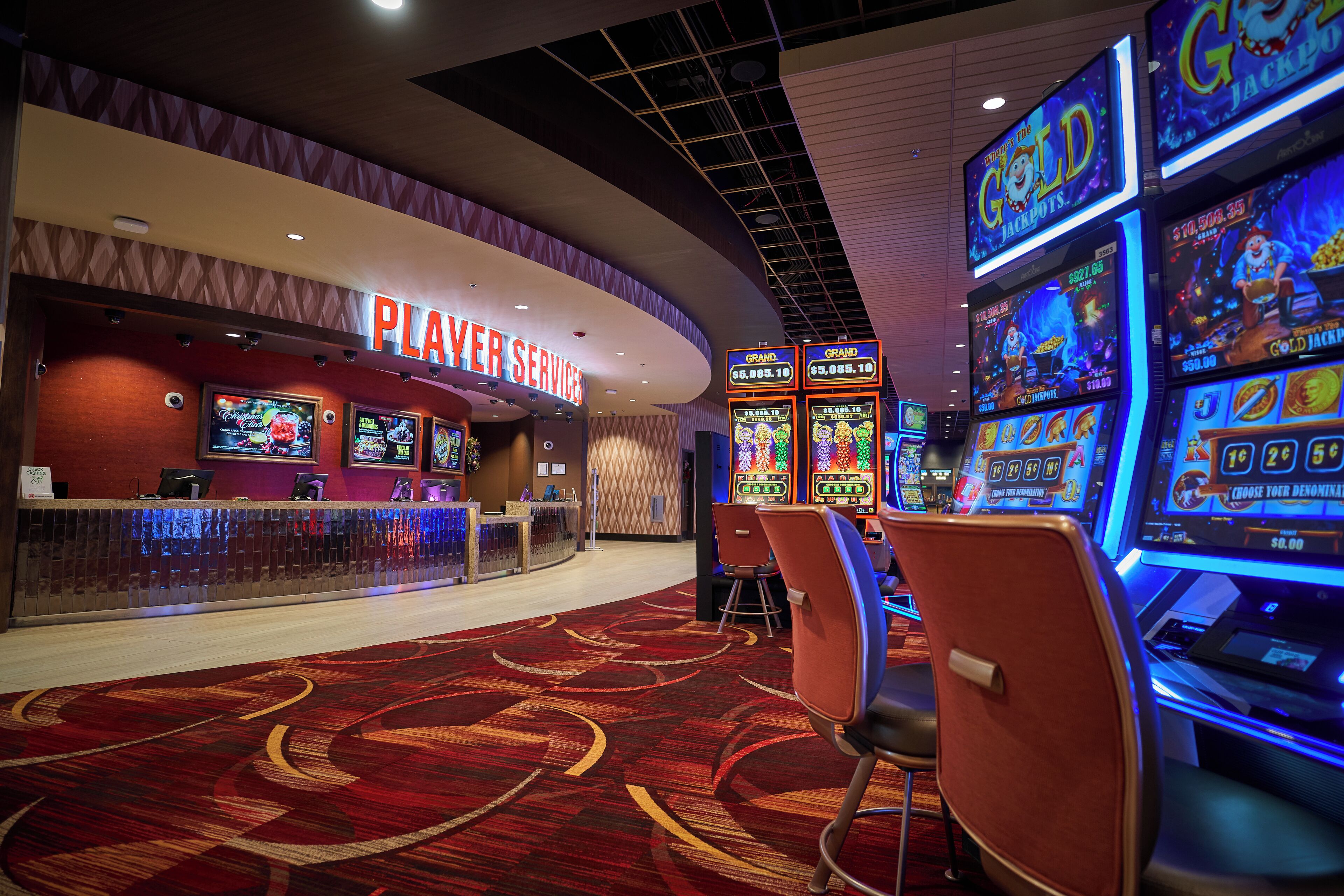 A casino area with slot machines, a player services counter, and a carpeted floor.