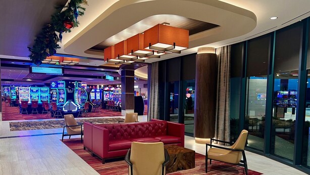 A modern lobby with a red sofa, beige chairs, and a wooden coffee table.