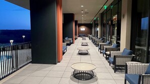 A corridor with seating areas, a view of the sky, and a railing.