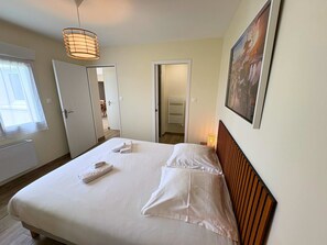 Une chambre d’hôtel avec un lit, une fenêtre, une porte, un radiateur et un tableau au mur.