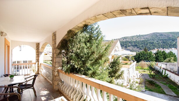 Un balcon donnant sur une colline et des bâtiments.