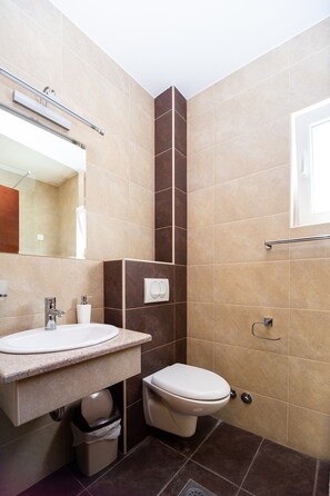 A bathroom with a sink, toilet, and mirror. - IPERA (Budva)