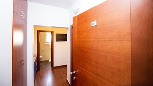 Un couloir avec des portes en bois, un panneau indiquant le numéro de la porte et une petite fenêtre.