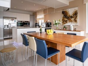 Une cuisine moderne dotée d’appareils électroménagers en acier inoxydable, d’une table à manger en bois et de chaises bleues.
