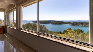 A room with large windows overlooking a lake and forested area. - Villa Rab Hills with Swimming Pool (Rab)