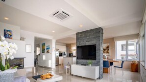 A modern living room with a stone fireplace, a flat-screen TV, and a dining area with a bar. - Villa Rab Hills with Swimming Pool (Rab)