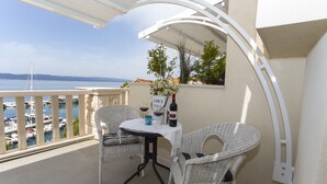 A balcony with a table and two wicker chairs, overlooking a marina with boats and a clear sky. - Apartments & Room Vesna - Studio Apartment with Terrace and Sea View (Brela)