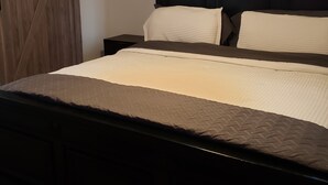 A bedroom with a large bed, dark headboard, and a wooden barn-style door. - home sweet home (Rex)