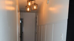 A narrow hallway with wooden flooring, white walls, and a ceiling light fixture. - home sweet home (Rex)