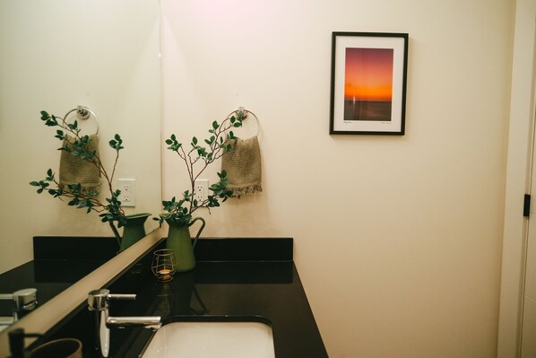 A bathroom with a sink, mirror, towel rack, and a framed picture on the wall.